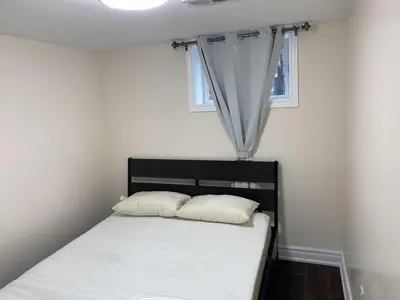 a bed with two pillows in a room with a window at Adorable private 2 bedroom basement unit in Toronto