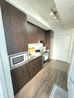 a large kitchen with wooden cabinets and a microwave at Amazing one bedroom suite with panoramic downtown views in Toronto