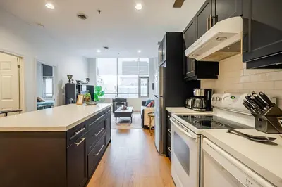 a kitchen with black cabinets and a white stove top oven at The Artist Loft Trendy 2BR Condo with Parking in Toronto