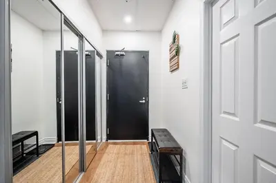 a hallway with a black door and a wooden floor at The Artist Loft Trendy 2BR Condo with Parking in Toronto