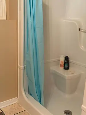 a bathroom with a blue shower curtain next to a toilet at Cozy Private Basement Apartment in Fort Erie in Fort Erie