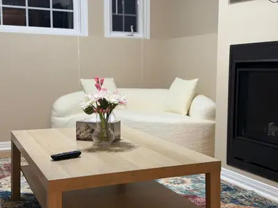 a living room with a vase of flowers on a coffee table at Cozy Private Basement Apartment in Fort Erie in Fort Erie