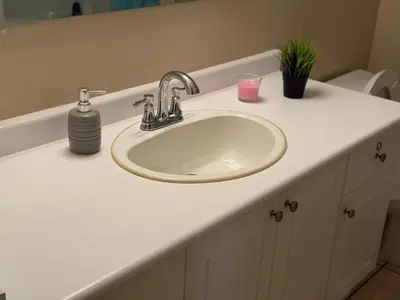 a bathroom sink with a soap dispenser and a pink candle at Cozy Private Basement Apartment in Fort Erie in Fort Erie