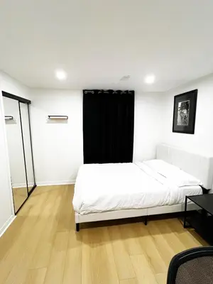 a bedroom with a white bed and a black curtain at Stunning Partially Renovated Apartment in Toronto