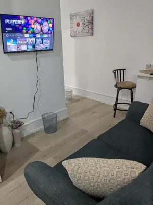a living room with a couch and a tv on the wall at Brand New Private Unit with Parking, Steps to TTC, 15 Minutes to Downtown in Toronto