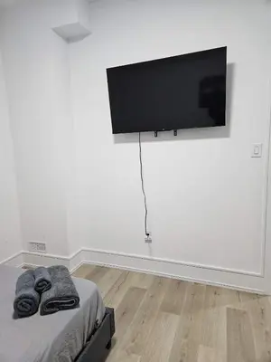 a bedroom with a bed with a flat screen tv on the wall at Brand New Private Unit with Parking, Steps to TTC, 15 Minutes to Downtown in Toronto