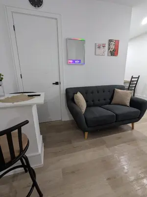 a living room with a black couch and a table at Brand New Private Unit with Parking, Steps to TTC, 15 Minutes to Downtown in Toronto