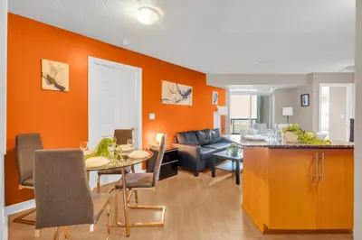 a living room with an orange wall and a table at 2 bedroom spacious apartment in Mississauga in Mississauga