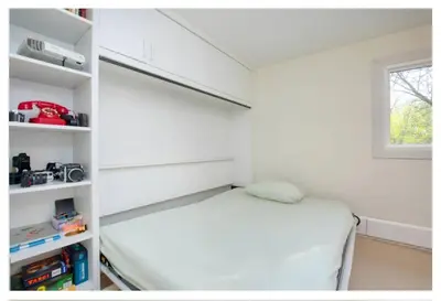 a small white room with a bed and a window at Picturesque 3-story townhouse in Toronto