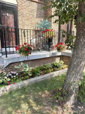a porch with flowers and a fence and a dog at Pau-Rae's Cozy Spot - your home away from home! in Thornhill