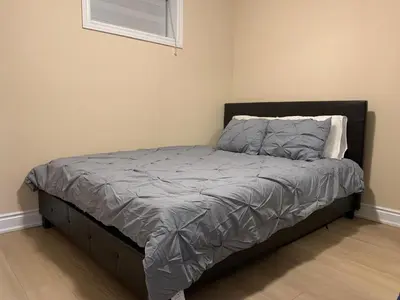 a bed with a gray comforter in a bedroom at Landen court in Mississauga