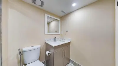 a bathroom with a toilet and a sink and a mirror at Landen court in Mississauga