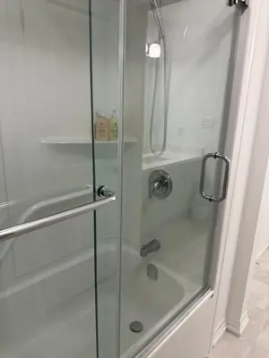 a shower with a glass door with a sink at K Niagara Guesthouse in Niagara Falls