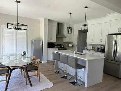 a kitchen with white cabinets and a glass table with a dining room at K Niagara Guesthouse in Niagara Falls