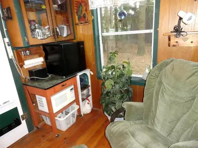 a living room with a tv and a chair at Cute Cozy Tiny House Surrounded by Trees for a Unique Couples Escape in Mt Forest, Ontario in Mount Forest