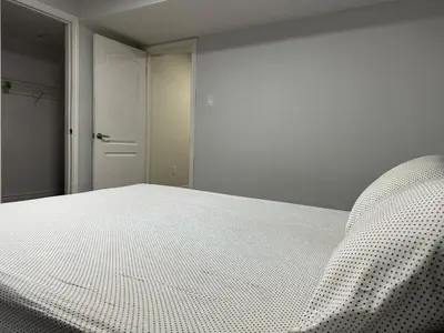 a bedroom with a white bed and a closet at New 2 bedroom basement in Cambridge in Cambridge