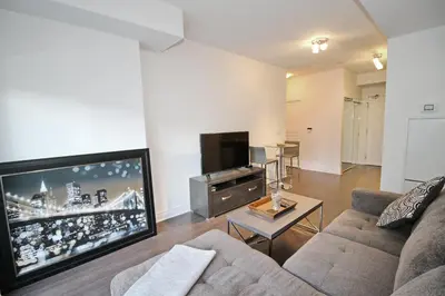 a living room with a couch and a flat screen tv at The Grand Avenue Suites - Downtown Toronto Entertainment District in Toronto