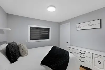 a white bedroom with a bed and a dresser at Welcome To Our Modern 2Bdrm,1Bth w, Laundry,BBQ in Welland