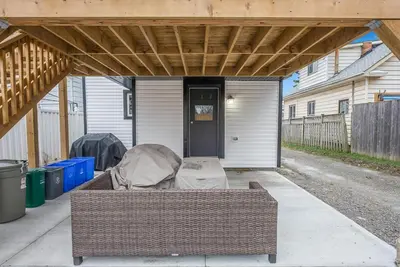 an outdoor patio with a wicker couch under awning at Welcome To Our Modern 2Bdrm,1Bth w, Laundry,BBQ in Welland