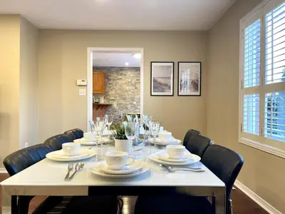 a dining room with a table with chairs and plates and glasses at Maison Laurier, Modern 5B4B Home Inc BSMT Free parking, Close to trails in Richmond Hill