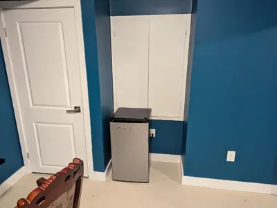 a room with a refrigerator and a blue wall at Sunshine room on Downsview in Toronto