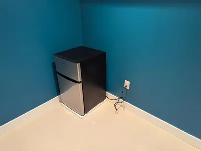 a black refrigerator in the corner of a room at Sunshine room on Downsview in Toronto