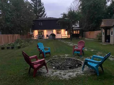four colorful chairs sitting in a yard in front of a house at 3 BDR lake Simcoe cottage-free parking -day pass to provincial park-one hour from Toronto in Georgina