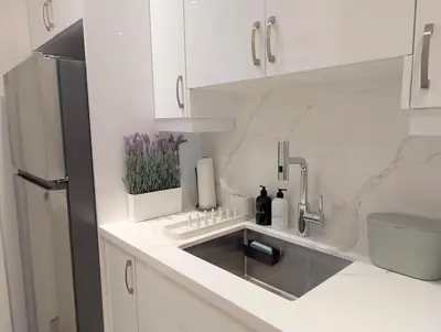 a white kitchen with a sink and a refrigerator at Luxury 1BR plus den walkout basement in Toronto