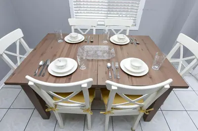 a wooden table with white chairs and plates and silverware at Entire 4BR 3BA Home in Mississauga, Sleeps 8, 10 mins to Pearson Airport in Mississauga