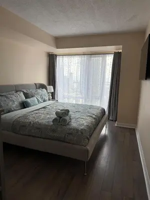a bedroom with a bed and a large window at Cozy & Elegant Condo-Lake & City View-35th floor in Toronto