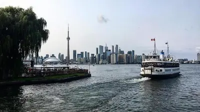 a boat on a river with a city in the background at Cozy & Elegant Condo-Lake & City View-35th floor in Toronto