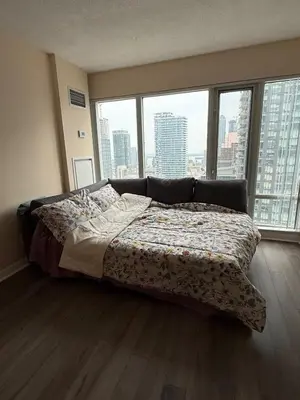 a bed in a bedroom with a large window at Cozy & Elegant Condo-Lake & City View-35th floor in Toronto