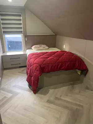 a bedroom with a bed with a red comforter and a window at Modern 7 Bedroom Masterpiece on Portage Sleeps 16 in Niagara Falls