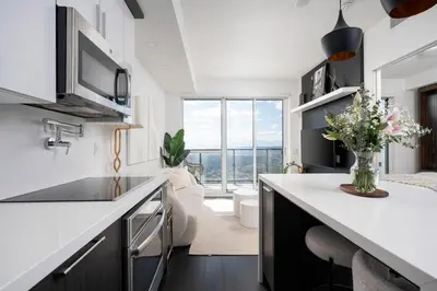 a kitchen with white countertops and a large window at Elegant Sunset Lake View Suite with Parking in Toronto