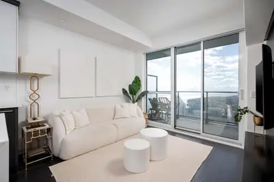 a living room with a white couch and a large window at Elegant Sunset Lake View Suite with Parking in Toronto