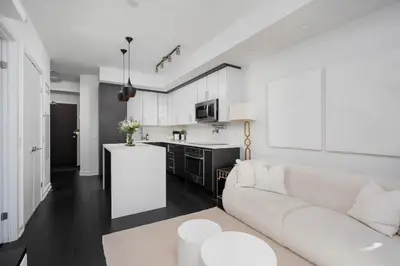 a white living room with a couch and a kitchen at Elegant Sunset Lake View Suite with Parking in Toronto