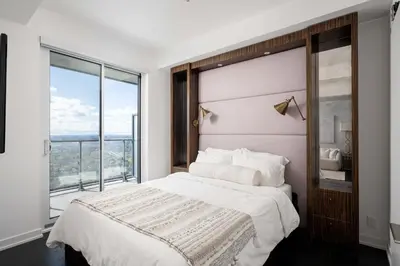 a bedroom with a large bed and a large window at Elegant Sunset Lake View Suite with Parking in Toronto