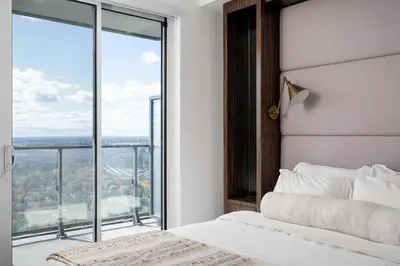 a bedroom with a bed and a large window at Elegant Sunset Lake View Suite with Parking in Toronto