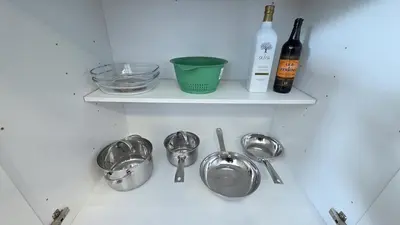 a shelf with three pans and a bottle of wine at Nordic Three Brantford in Brantford