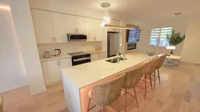 a kitchen with white cabinets and a bar with chairs at Nordic Three Brantford in Brantford