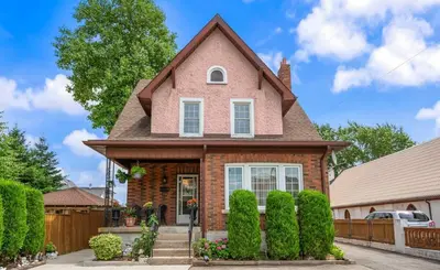 a pink house with a fence at Romeo & Juliet Niagara Retreat - Clifton Hill in Niagara Falls