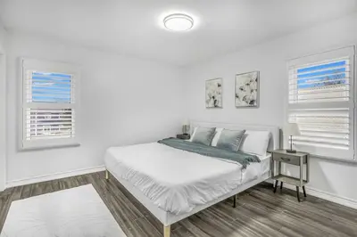 a white bedroom with a bed and two windows at Romeo & Juliet Niagara Retreat - Clifton Hill in Niagara Falls