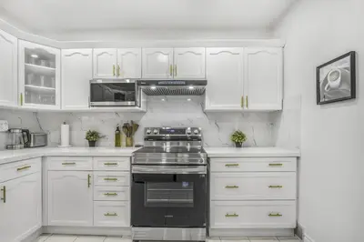 a kitchen with white cabinets and a stove top oven at Romeo & Juliet Niagara Retreat - Clifton Hill in Niagara Falls