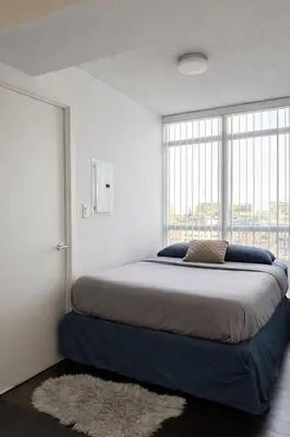 a bedroom with a large bed with a large window at Fully furnished Lux 1bedroom condo in Toronto