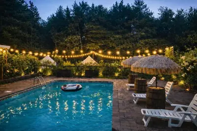 a pool with lights and chairs and a raft in the water at Peaceful Forest Retreat with Fire Pit and BBQ near Mansfield Ski Club in Mulmur