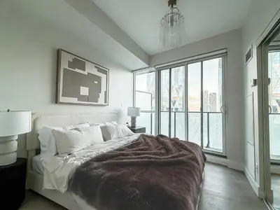 a white bedroom with a bed and a large window at 40th Fl Designer Lakeview 2BR PATH & Union Access in Toronto