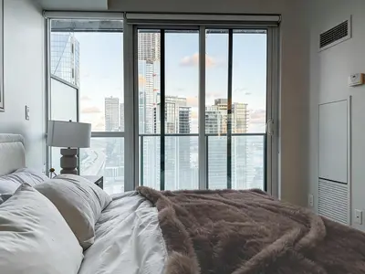 a bedroom with a bed and a large window at 40th Fl Designer Lakeview 2BR PATH & Union Access in Toronto