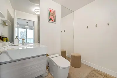 a white bathroom with a toilet and a sink at 40th Fl Designer Lakeview 2BR PATH & Union Access in Toronto
