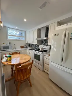 a kitchen with a wooden table and a white refrigerator at Bachelor Suite Near Transit - Private Stay in Toronto Registration number STR-2503-FSHPPQ in Toronto