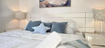 a white bed with blue pillows in a bedroom at Luxury 3BR Near Pearson Airport Free Parking in Toronto